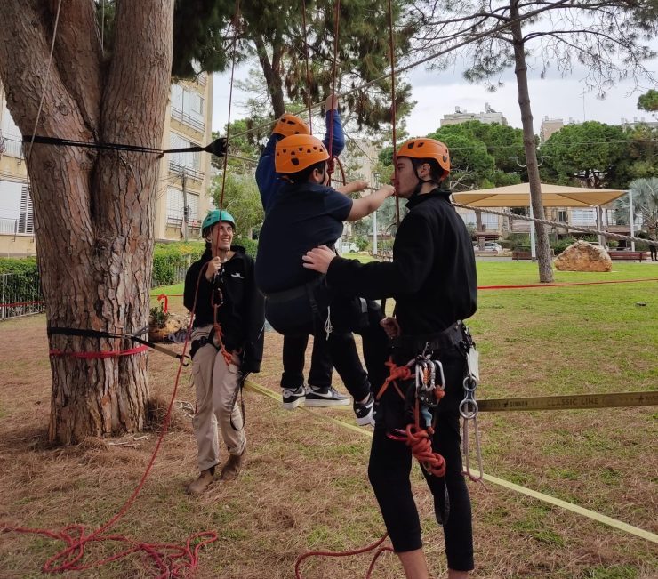 פעילות חבל באתגרים, 2 מדריכים עוזרים לילדים לטפס על רשת חבל שפרושה בין 2 עצים